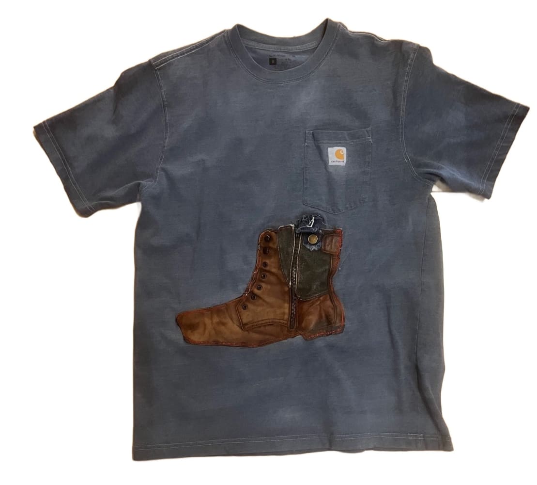 A faded blue Carhartt t-shirt with a brown work boot graphic.