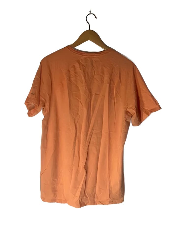 Peach-colored short-sleeved t-shirt on a wooden hanger.