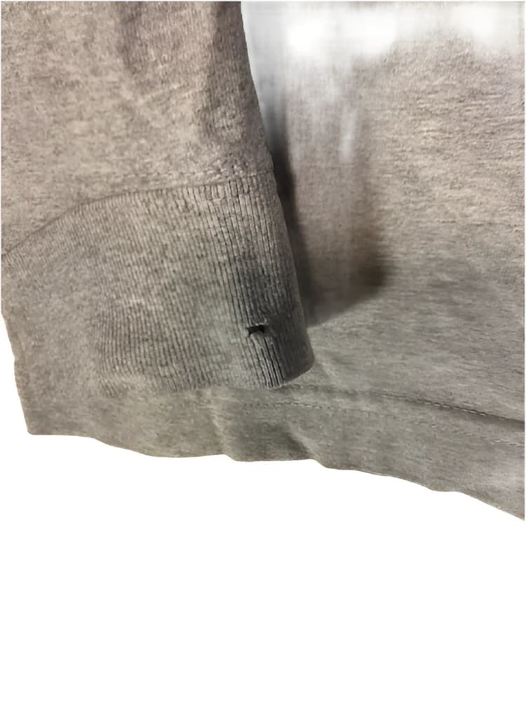 Gray sweatshirt with a small tear.