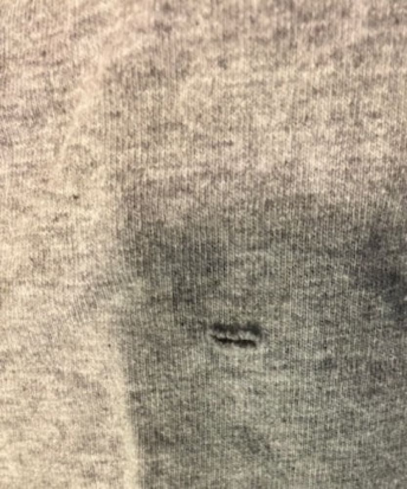 Gray fabric with a small horizontal tear.