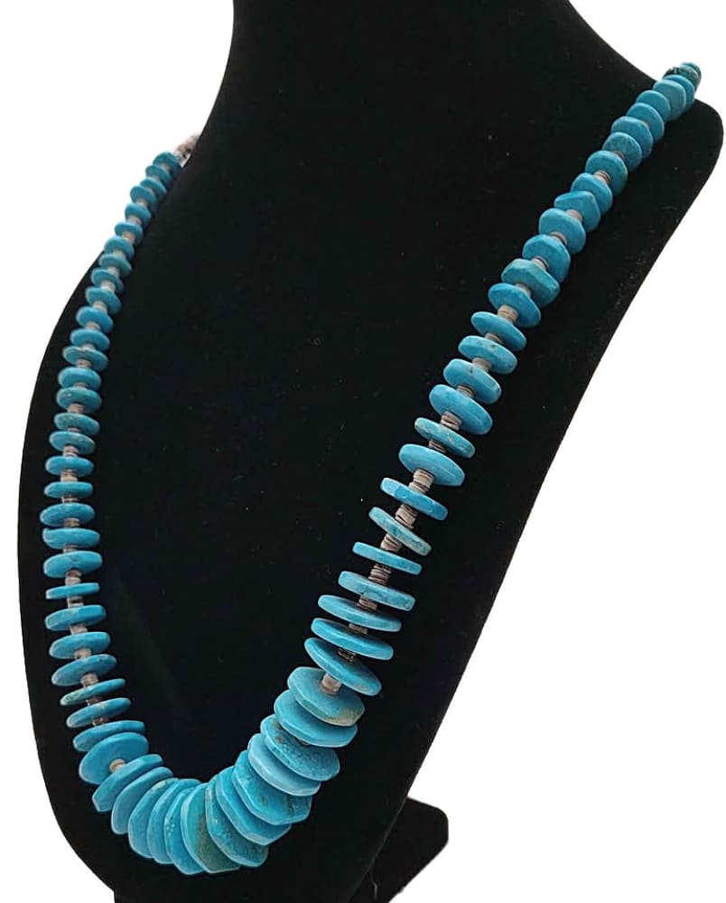 A turquoise disc beaded necklace on a black display.