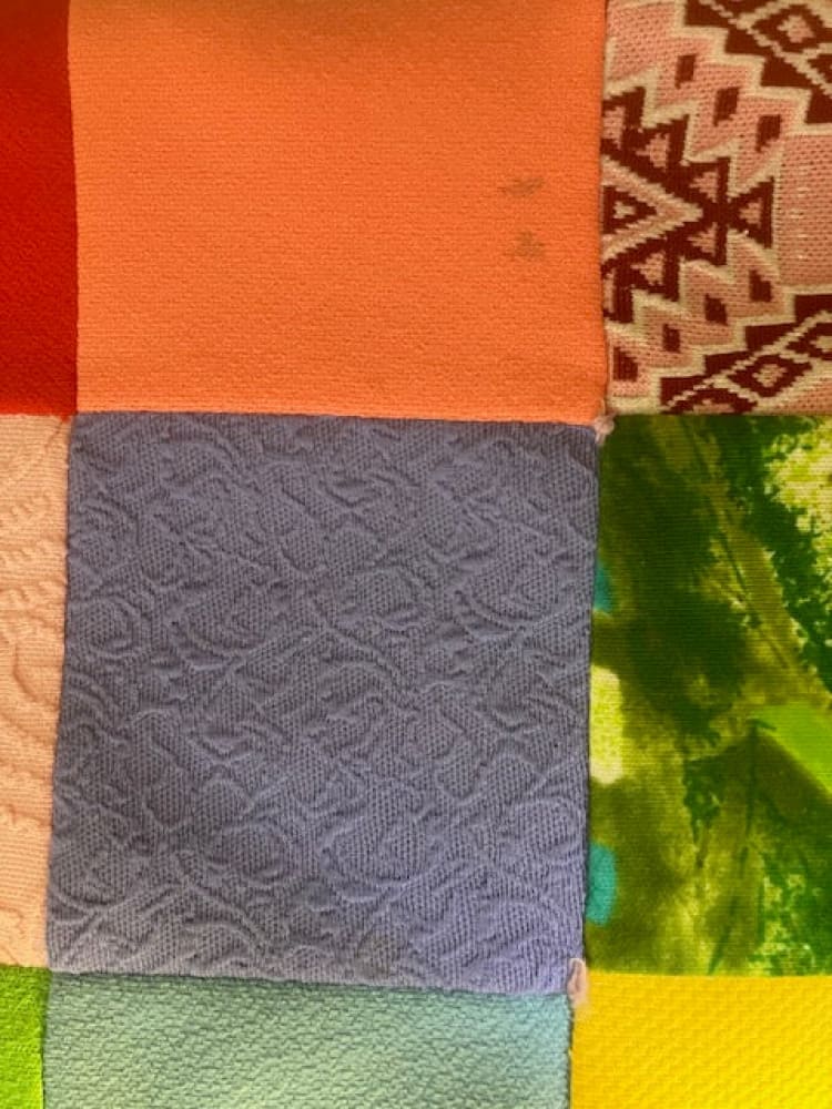 A patchwork quilt or fabric sampler with various textures and colors.