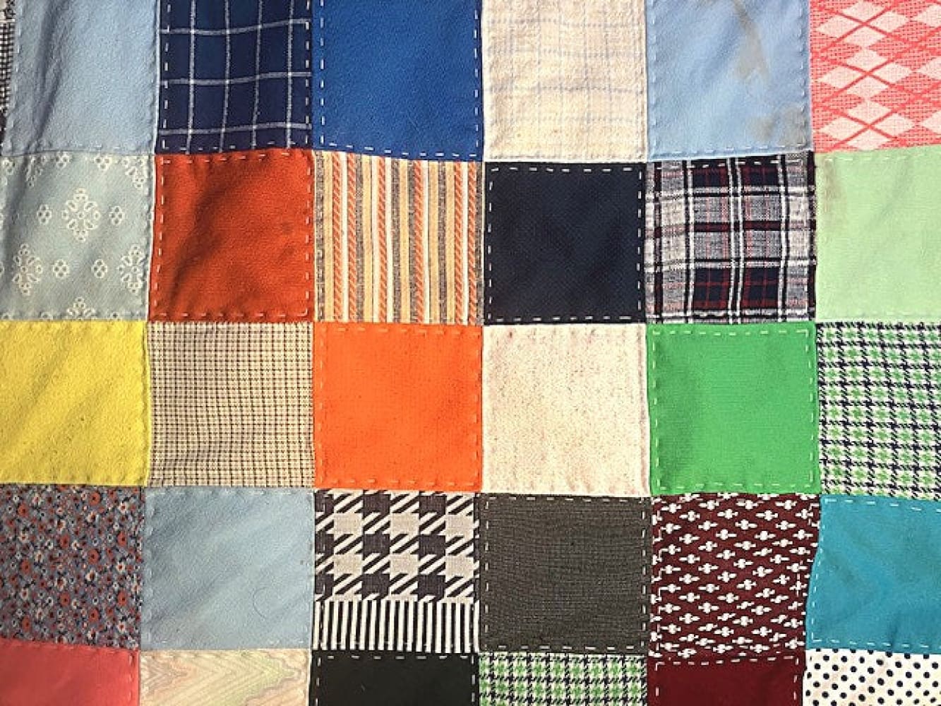 A handmade patchwork quilt with various fabric patterns and colors, stitched together.