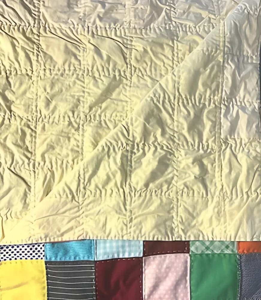 Yellow quilted fabric with a colorful patchwork border.