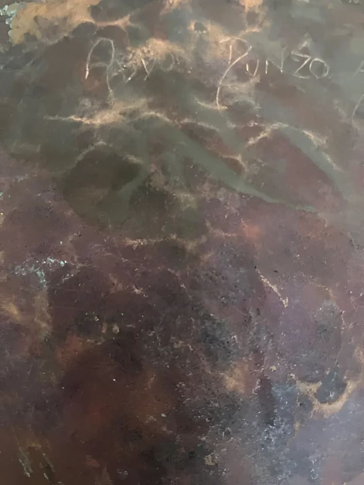 Dark, textured surface with faded writing.