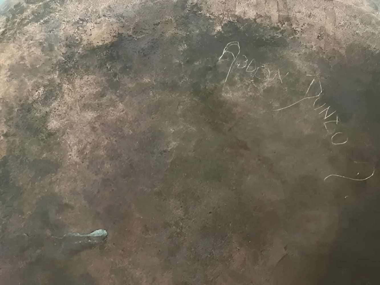 Close-up of engraved signature Abdon Punzo on hammered copper vase surface