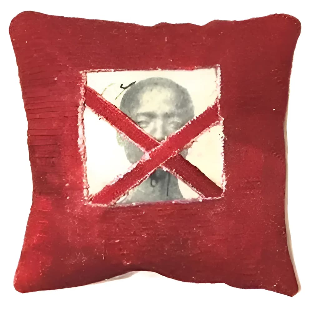 Red pillow with crossed-out portrait.