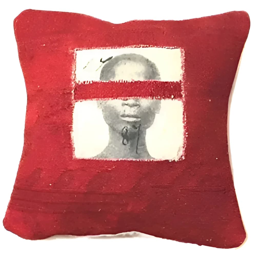 Red pillow with obscured portrait.