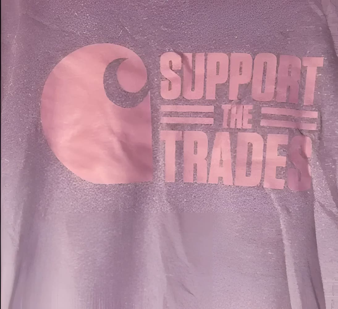 A gray t-shirt with a pink ’Support the Trades’ graphic and a Carhartt logo.