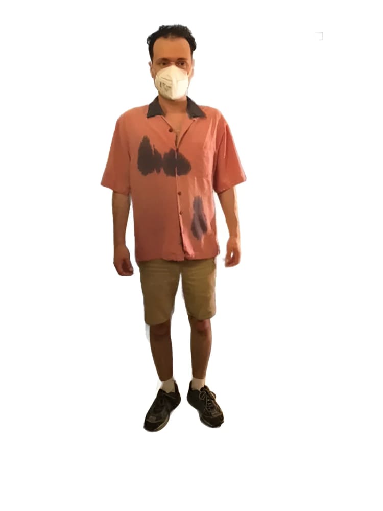 Man wearing a face mask, pink shirt, and khaki shorts.