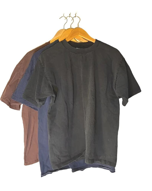 Three plain t-shirts in brown, blue, and black, hanging on wooden hangers.