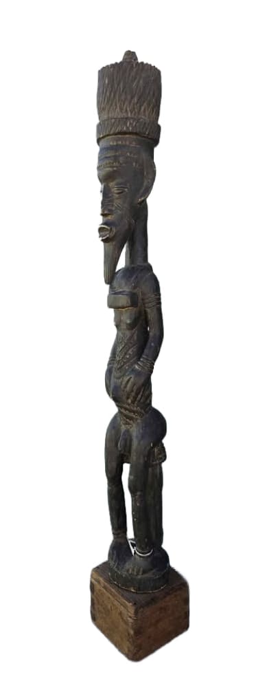 Dark wooden tribal figure with a large headdress and elongated features.
