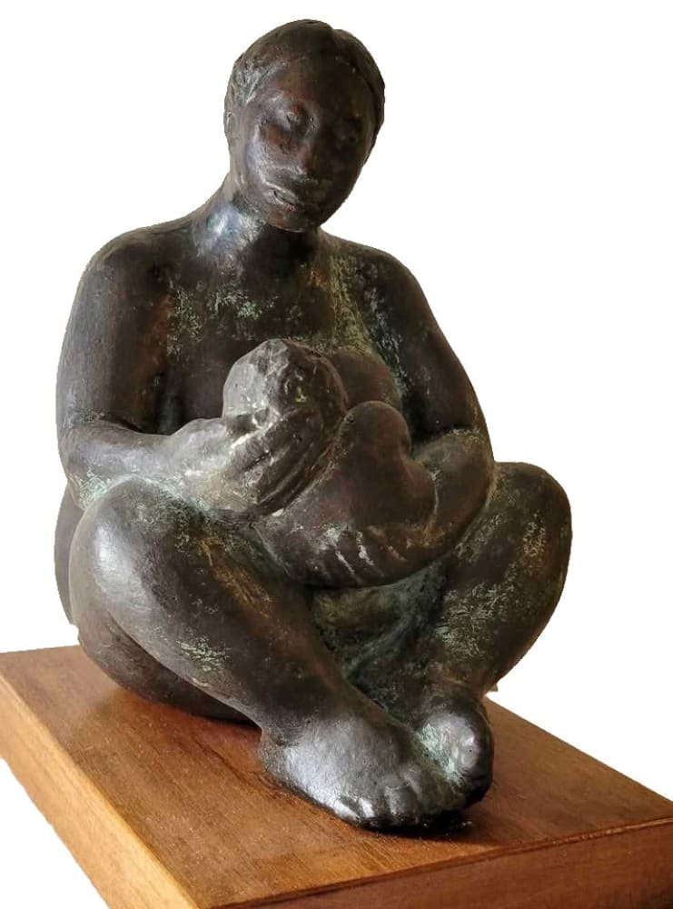 A dark bronze sculpture of a mother cradling a baby.