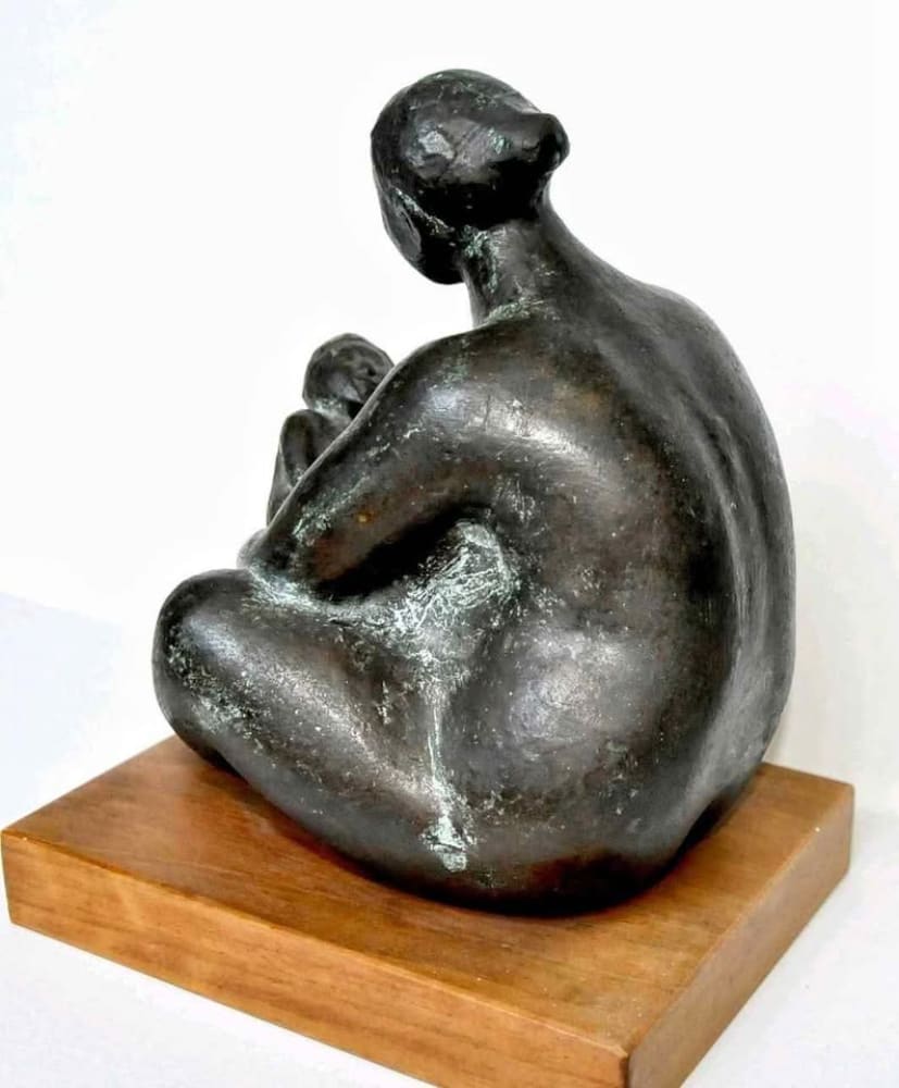 A dark bronze sculpture of a seated woman holding a child.
