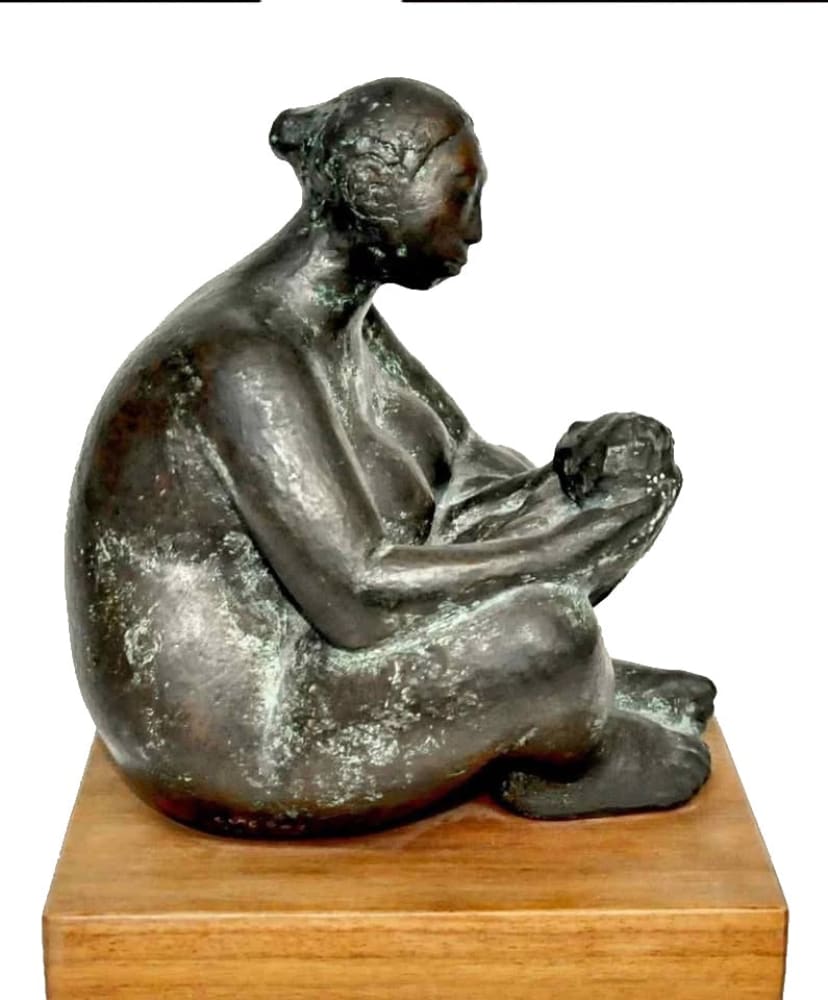 A bronze sculpture of a seated woman cradling a child.