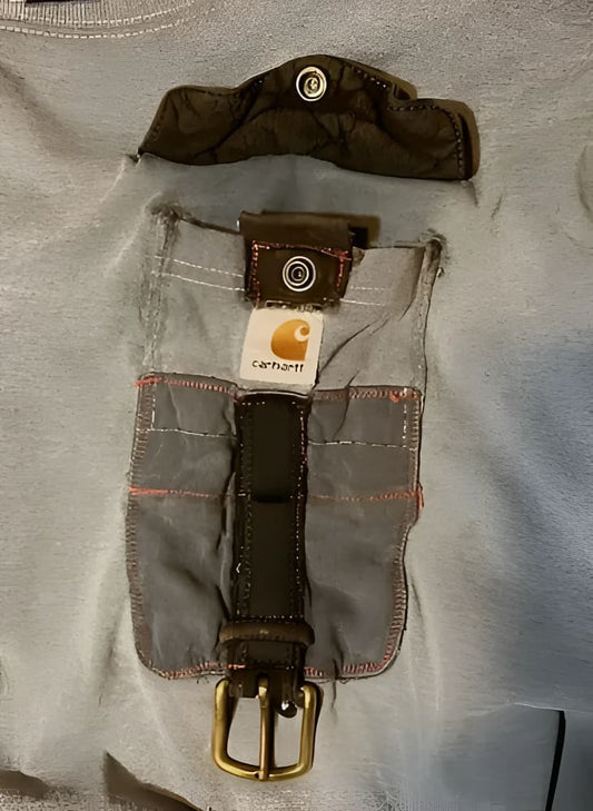 A grey t-shirt with a unique pocket design featuring a brown leather strap and brass buckle, and a snap-button closure on a separate flap.