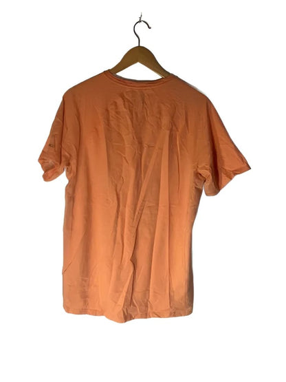 Peach-colored short-sleeved t-shirt on a wooden hanger.