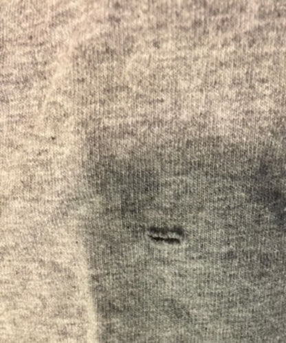 Gray fabric with a small horizontal tear.