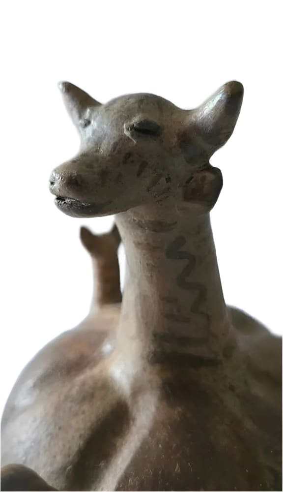 Ancient ceramic vessel in the shape of a stylized animal with a smaller animal on its back.