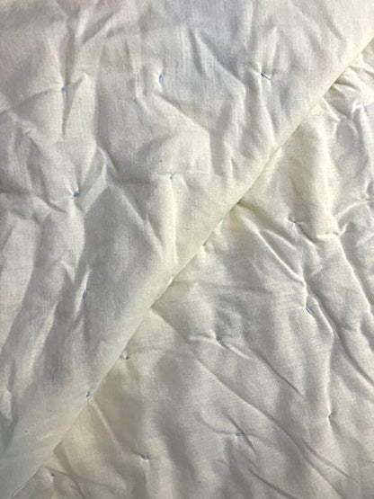 White quilted blanket with light blue stitching.