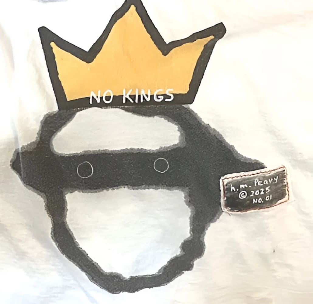 White t-shirt with black and yellow crown design, ’no kings’ text