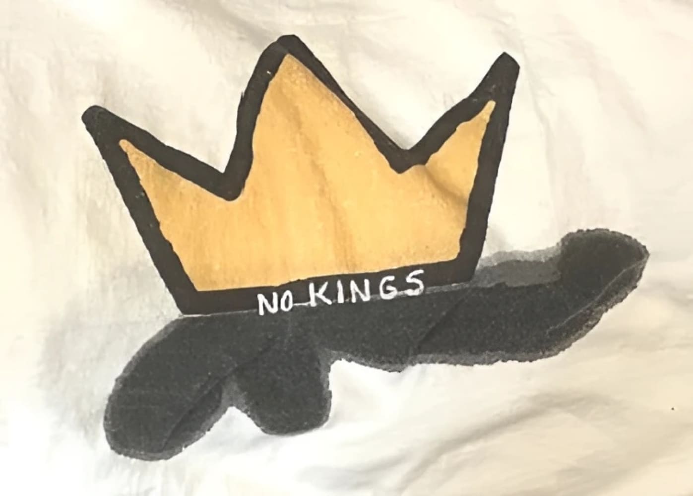 Yellow and black crown plush toy with ’no-kings’ text.