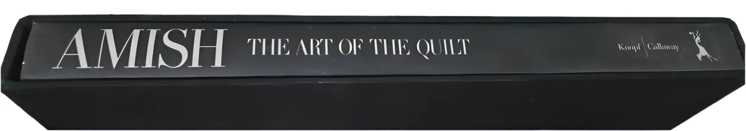 A black book titled ’AMISH THE ART OF THE QUILT’.