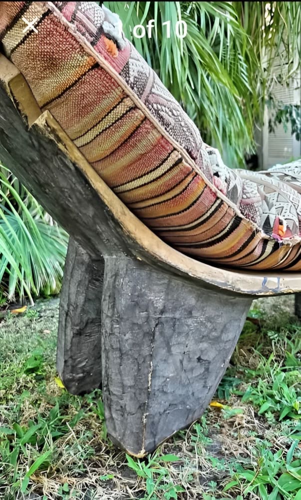 Hand-carved wooden chaise lounge with a striped, patterned cushion.