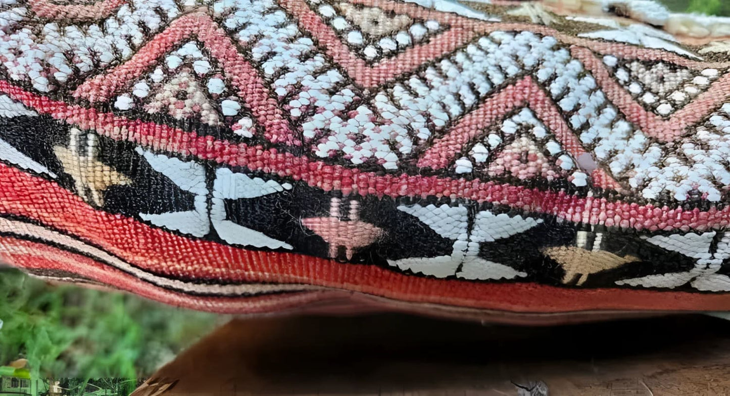 A woven textile with geometric patterns in shades of red, white, black, and tan.