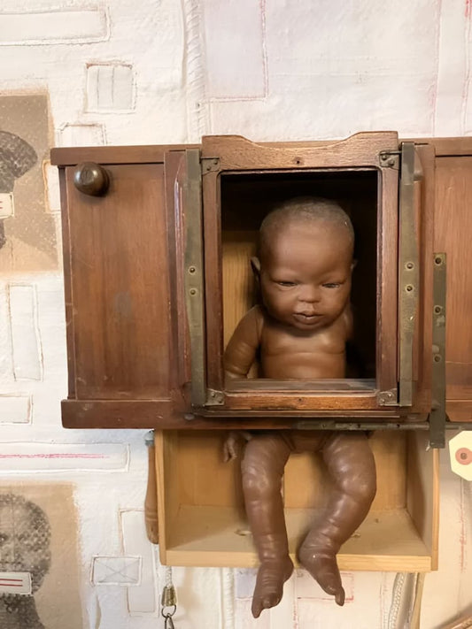 Antique doll in wooden cabinet.