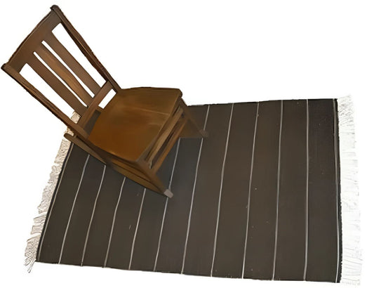 Wooden rocking chair on striped rug.