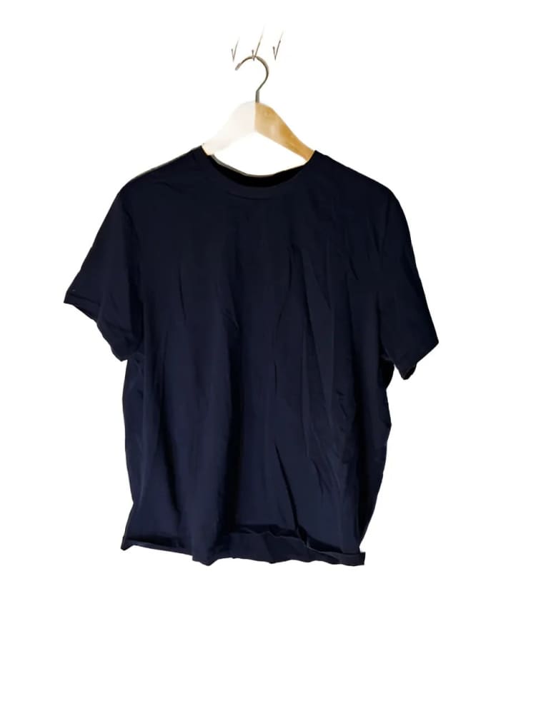 A dark blue short-sleeved t-shirt on a wooden and white hanger.