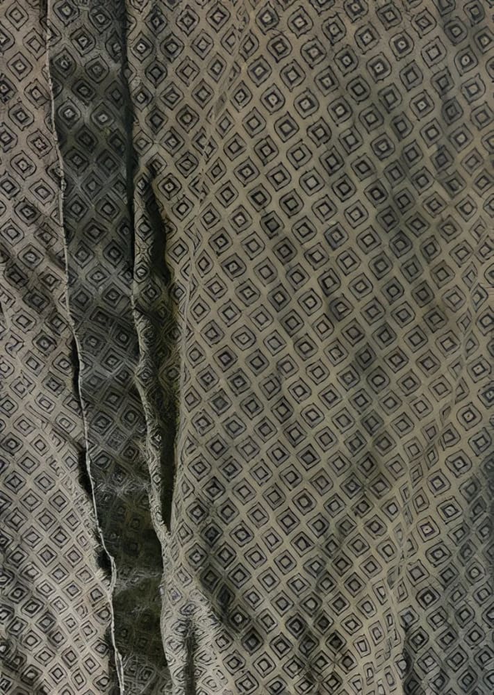 Wrinkled gray fabric with a repeating diamond pattern.