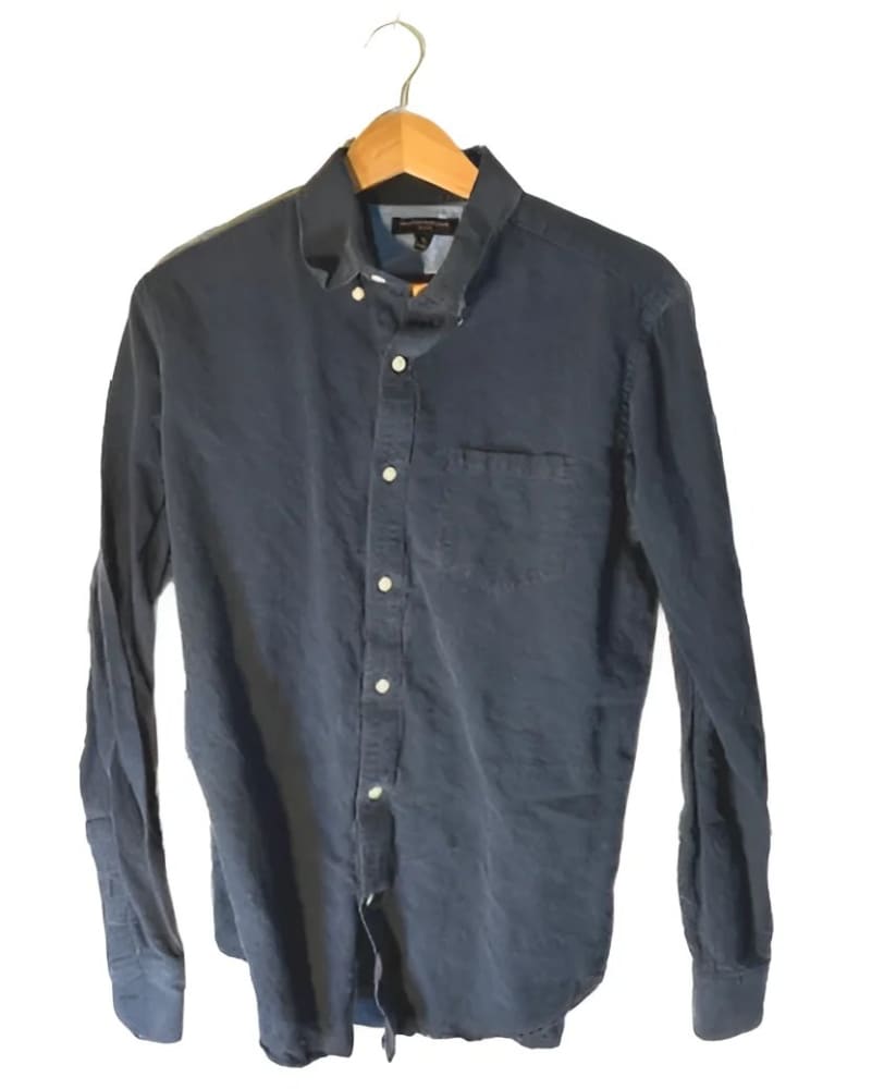 Men’s long-sleeved dark blue button-down shirt with a single chest pocket, hanging on a wooden hanger.