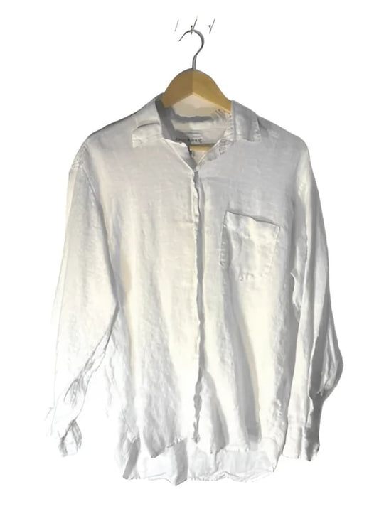 White linen long-sleeve button-up shirt with a single chest pocket, hanging on a wooden hanger.
