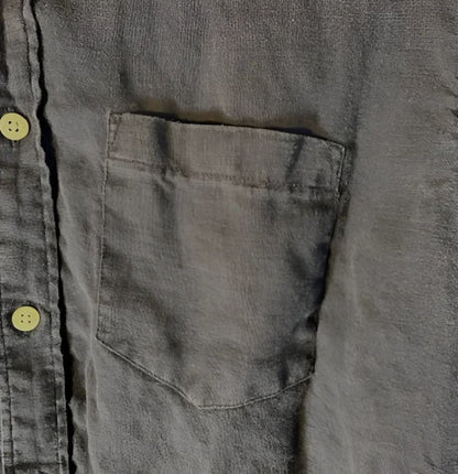 Dark gray linen shirt with a single breast pocket and light yellow buttons.
