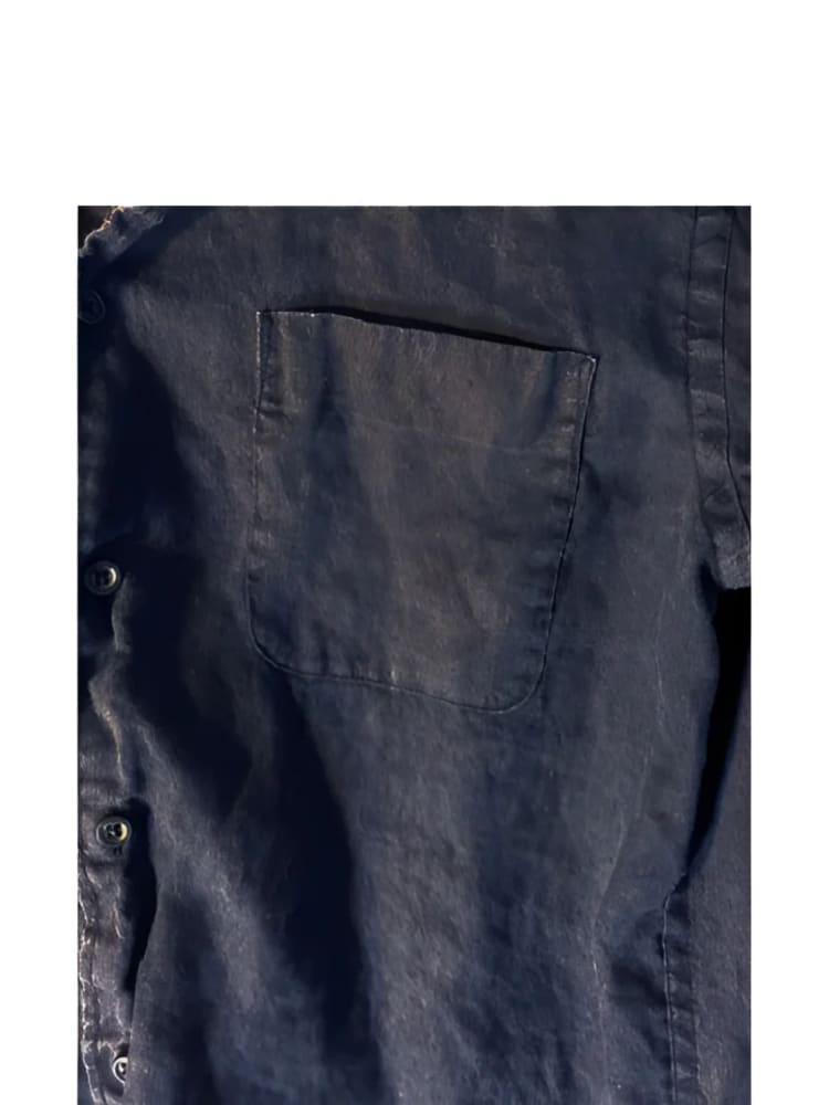 Dark blue, faded denim shirt with a single breast pocket and visible buttons.