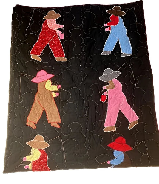 Hand-stitched quilt with appliquéd figures of people in overalls and hats, holding buckets and fishing poles, on a black background.