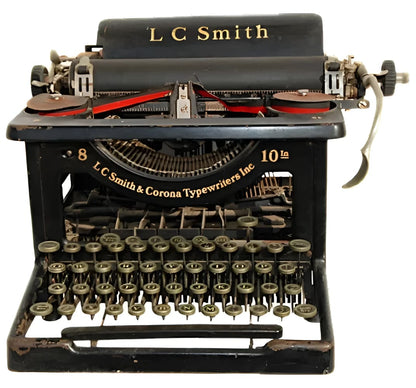 An antique black L.C. Smith typewriter with a full QWERTY keyboard and red ribbon.