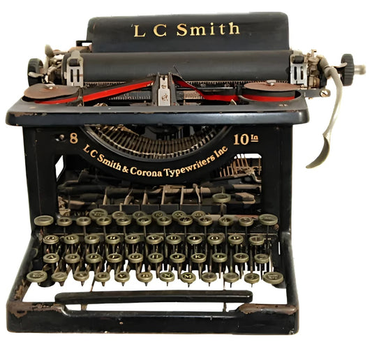 An antique black L.C. Smith typewriter with a full QWERTY keyboard and red ribbon.
