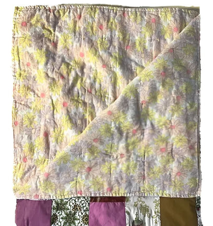 A floral patchwork quilt with yellow, pink, and purple patterns.