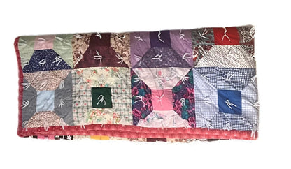 Handmade patchwork quilt with a ’log cabin’ pattern and various fabrics.