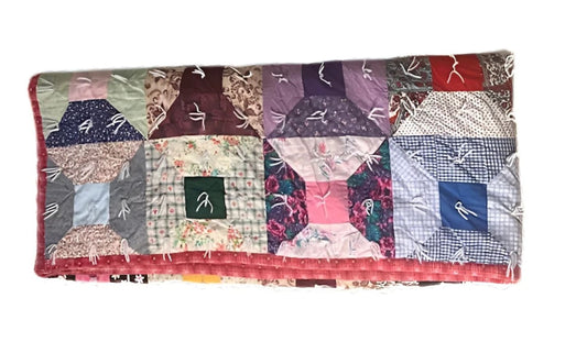 Handmade patchwork quilt with a ’log cabin’ pattern and various fabrics.