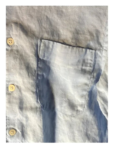 Light blue linen shirt with a single breast pocket and visible buttons.