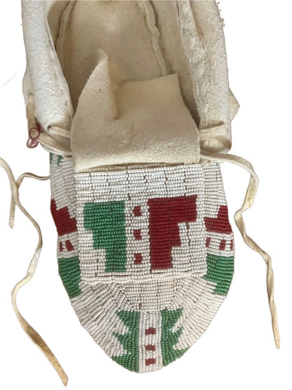 A white deerskin Native American beaded pouch with red and green geometric patterns.