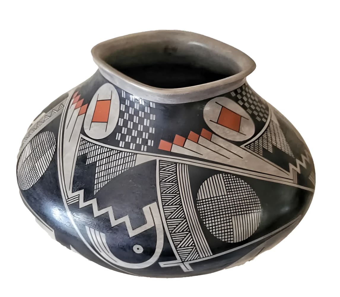A black pottery vessel with intricate geometric patterns in white, gray, and orange.