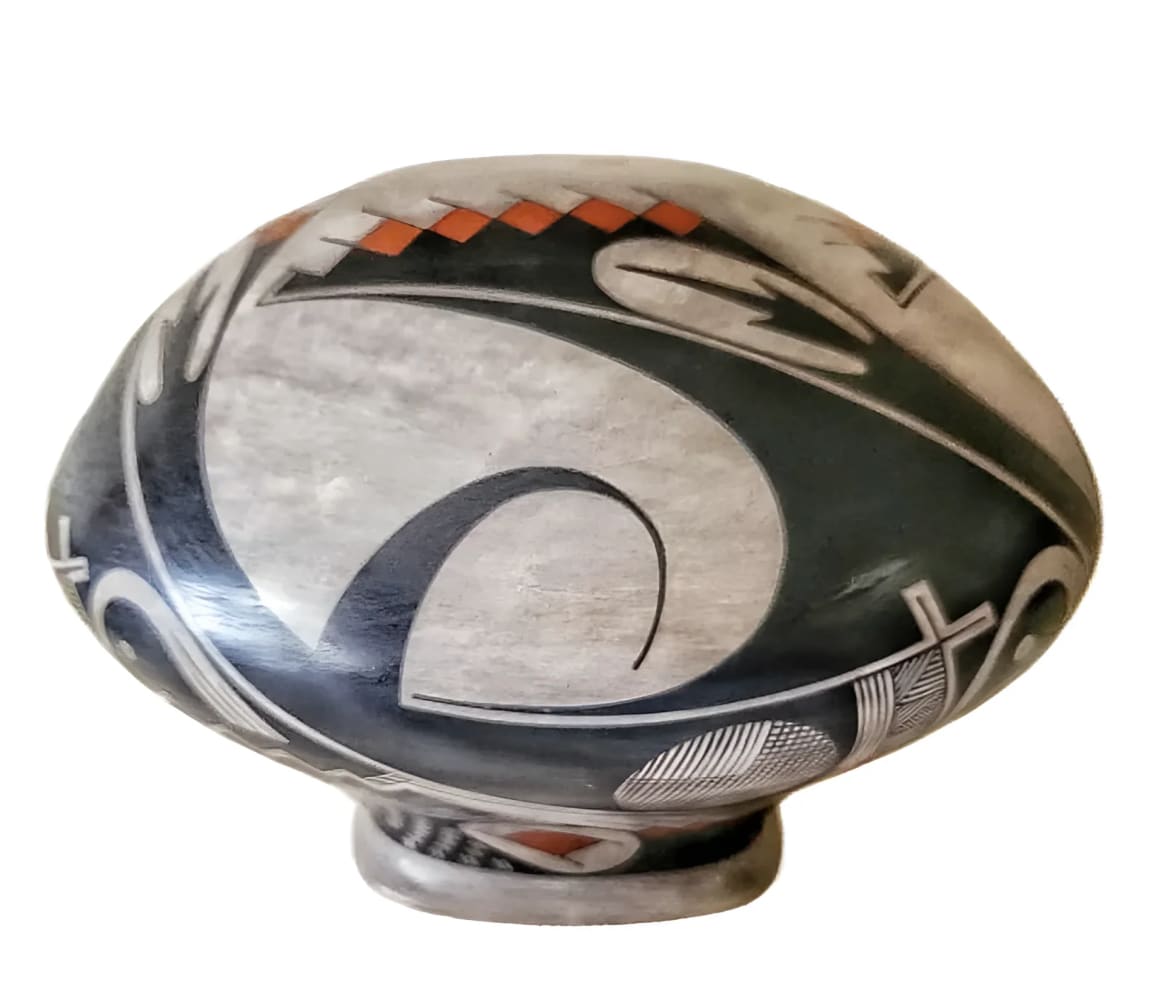 A black and white ceramic pot with a rounded body, a flared base, and a geometric pattern featuring a prominent swirl and orange accents.