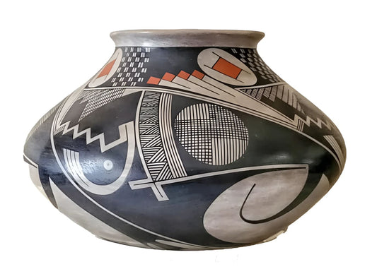 A wide-mouthed, black and white ceramic pot with intricate geometric and abstract designs, accented with terra cotta and white elements.