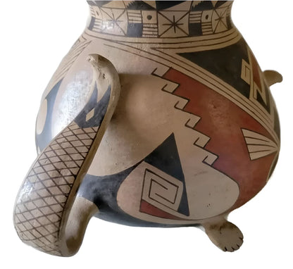 A traditional Native American pottery vessel with intricate geometric patterns in black, white, and red, featuring a unique textured handle and small feet.
