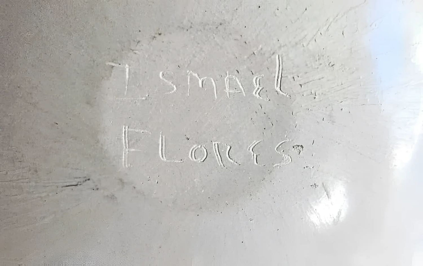 White, textured surface with faint, carved writing.